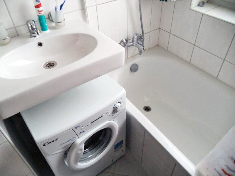 Washing machine under the sink in a small bathroom